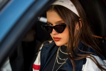 Beautiful cute teenage country girl in 90s style in car Back in time 80s. Stylish retro dressed in...