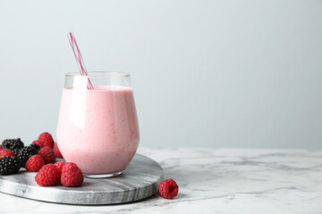 Yummy berry smoothie in glass on white marble table, space for text