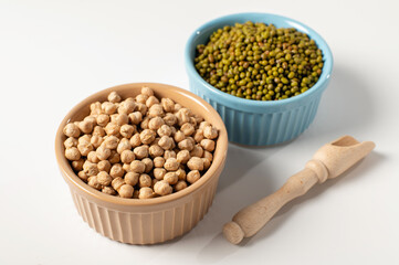 dry chickpeas, green mung bean, in a ceramic dish on a white table