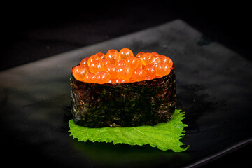 Gunkan Maki Sushi with salmon caviar (Ikura) and cucumber on black background. Sushi menu. Japanese food.