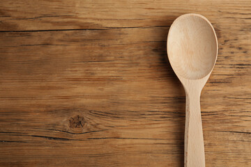 Handmade wooden spoon on rustic table, top view. Space for text