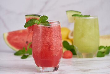 Refreshing summer citrus cocktail with lemon, watermelon and melon with mint and ice cubes in glass, homemade smoothies fresh fruit, fruit drink for healthy concept, selective focus.