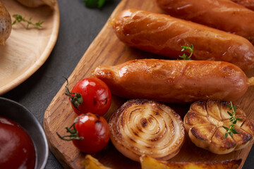 sausages and ingredients for cooking. Grilled sausage with the addition of herbs and and spices, vegetables, rosemary, thyme on the grill plate, Grilling food, bbq, barbecue, on stone table. Top view.