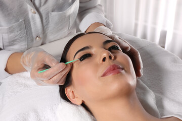 Obraz na płótnie Canvas Young woman undergoing eyelash lamination and tinting in salon