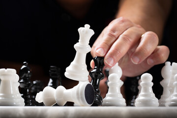 Chess player makes a check mate move with the black Queen against the white Queen and the King