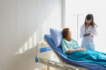 female doctor had a stethoscope analyzed  with standing and pointed and look at the tablet explaining to female patients lying in bed at hospital.