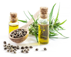 Cannabis seeds in the wooden spoon and bottles of hemp oil isolated on white background. Close up.