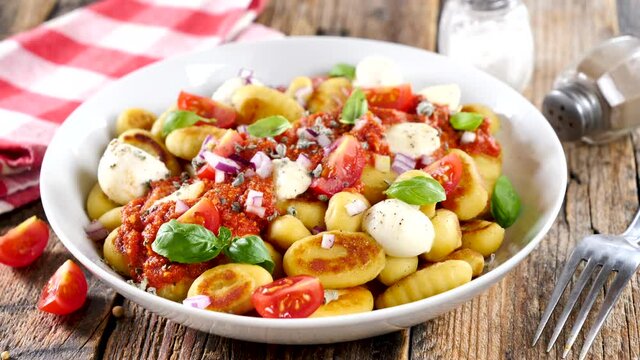 bowl of gnocchi, tomato , cheese and basil