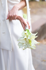 Obraz na płótnie Canvas modern wedding bouquet, white calla lilies. the bride holds a bouquet in her hands