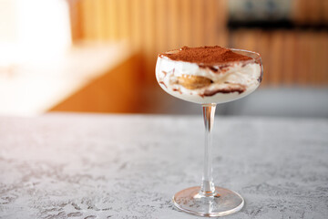 Tiramisu dessert in a glass on gray surface