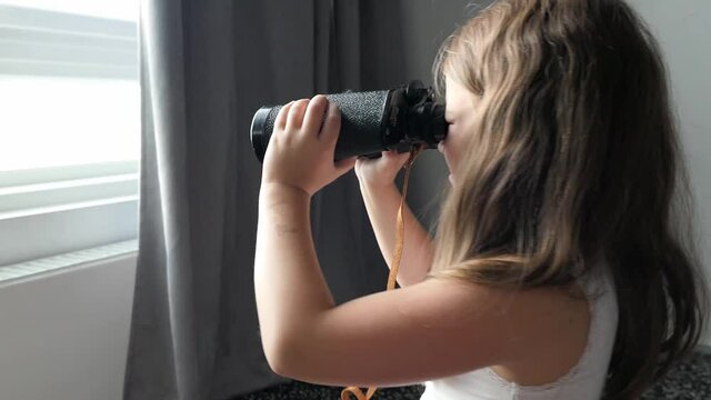 girl looks in black binoculars optical instrument watching