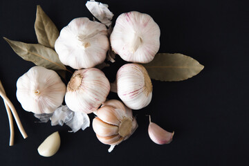 Aromatic garlic bulbs with spices, bay leaves and peppercorns on a black background. Condiments and spices. Natural remedies for strengthening immune system.
