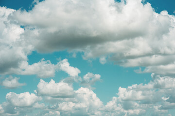 Background of a blue sky with large white clouds. Summer atmospheric background. Warm saturated colors