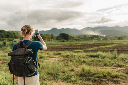 Backpacker tourist is making photo of sunset landscape