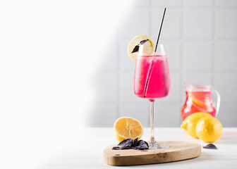 Refreshing lemonade made of red basil and lemon in a glass and in a jug. Copy space.