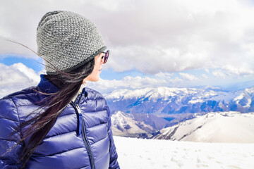 Fototapeta na wymiar Caucasian female person enjoy winter mountains panorama in sunny ski resort. Right empty blank space copypaste winter solo holiday background