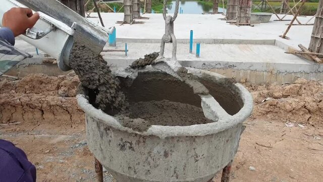 Worker load cement from truck to bucket in construction site.