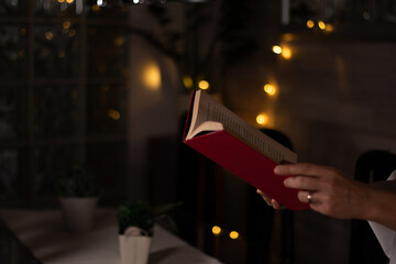 Lectura libro con tapa roja y fondo difuminado con luces amarillas