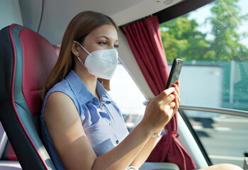 Side view of relaxed woman with KN95 FFP2 face mask using smart phone app. Bus passenger with...