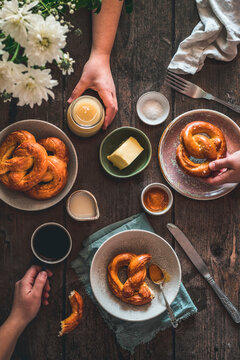 Pretzel Breakfast Scene, with people eating breakfast in a rustic kitchen with a wooden table