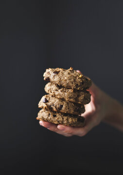 A Hand Holding A Stack Of Chocolate Chip Cookies