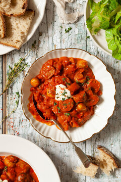 A bowl of sausage goulash served on a rustic table