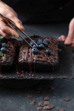 Pastry chef decorates brownie cake with blueberries and mint leaves