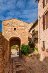 Spello charming historic center lane with Porta Sant'Angelo (Holy Angel) gate arch in the medieval walls
