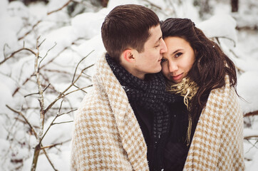 A guy and a girl in warm clothes and scarves on a walk in the snowy weather