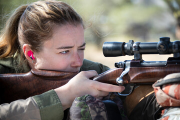Close-up of a woman shooting a rifle - obrazy, fototapety, plakaty
