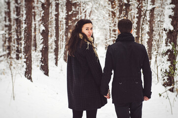 A guy and a girl in warm clothes and scarves on a walk in the snowy weather