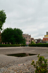 Obraz premium Stones leading to an artificial pond and at the back, buildings from downtown