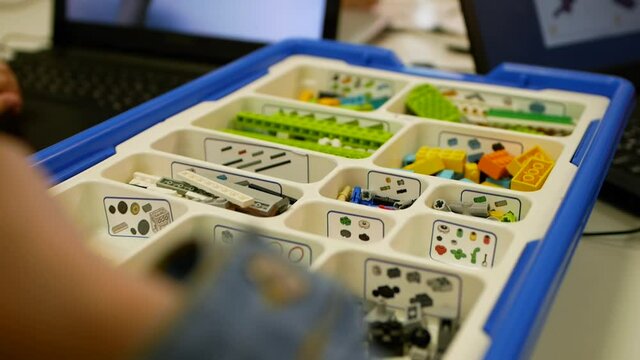 Close-up of a student's hand in an engineering class making a robot. Robotics education. Children play with toys from building blocks. Colorful constructor in a box. An entertaining educational game.