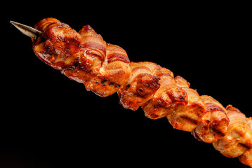 Barbecue turkey breast with bacon on skewers on black background. Brazilian gastronomy.