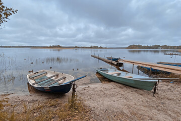 Naklejka na ściany i meble Rowing boat on the shores of Lake Seliger. Walkway on a sandy beach on a cloudy day