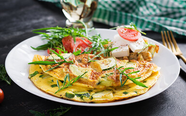 Omelette with zucchini, green herbs and sandwich with feta cheese on plate.  Frittata - italian omelet.