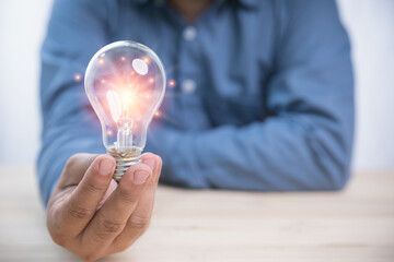 Obraz na płótnie Canvas Idea concept inspiration and innovation. Businessman holding a bright light bulb with copy space. Creativity innovation ideas for the future.