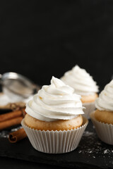 Fototapeta na wymiar Delicious cupcakes with cream and cinnamon on slate board, closeup