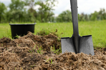 Shovel in soil outdoors, space for text. Gardening tool