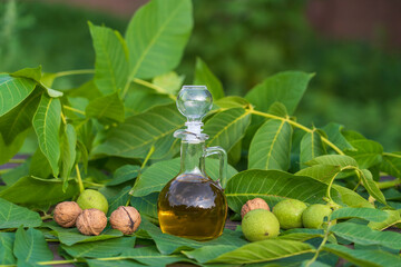 Walnut oil in a glass bottle and nuts on nature background, close up