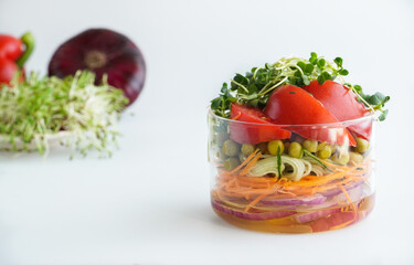 A snack of raw vegetables in a glass. Bright vegetables on a white background