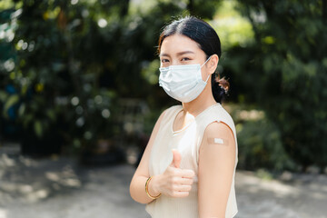 Healthy asian young teenager woman wear medical face mask giving thumbs up to bandage after get...
