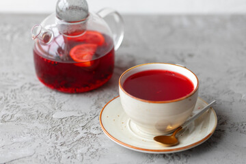 Berry tea in glass teapot on gray surface