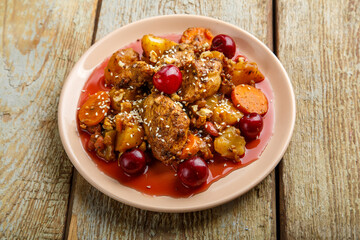 Jewish dish stewed potatoes with chicken in cherry sauce decorated with cherries.