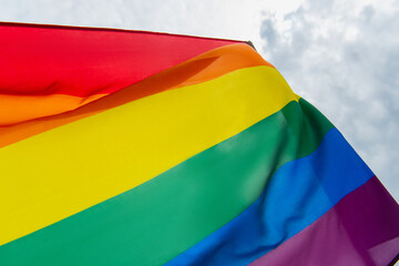 close up view of colorful lgbt flag against cloudy sky
