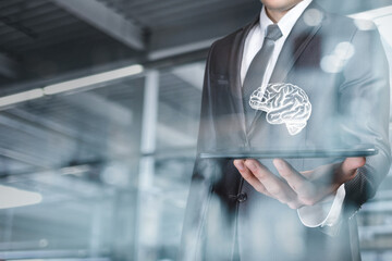 Businessman shows the brain on the tablet on a blurred background.