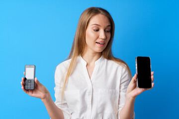 Young woman holding old and new telephone against blue background