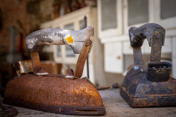 Two old rusty irons on the table. 