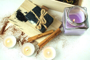 Block of natural carbon soap on a wooden board, burning spa candles
