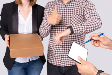 A young couple is very happy the courier delivered a package on time so they need to sign for it on the tablet.